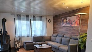 Una sala de estar moderna con un sofá seccional, una chimenea y un cuadro grande en la pared.