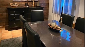 Un comedor moderno con una mesa de madera oscura, sillas negras y un mueble negro decorado con objetos.