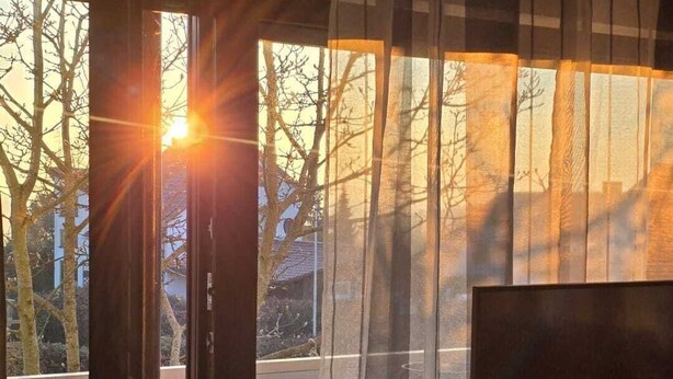 Una habitación con un ventanal grande, una puerta y un escritorio con una computadora.