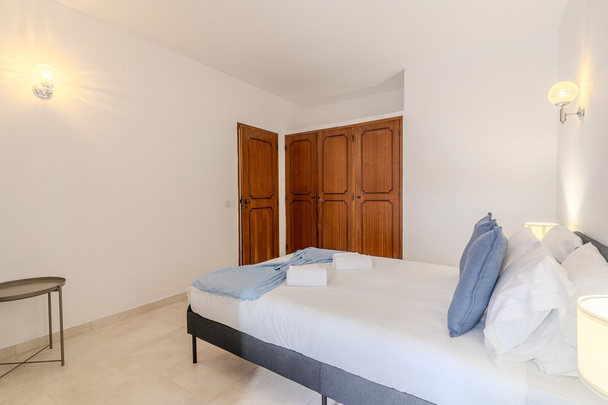 A bedroom with a bed, a bedside table, and a wardrobe.
