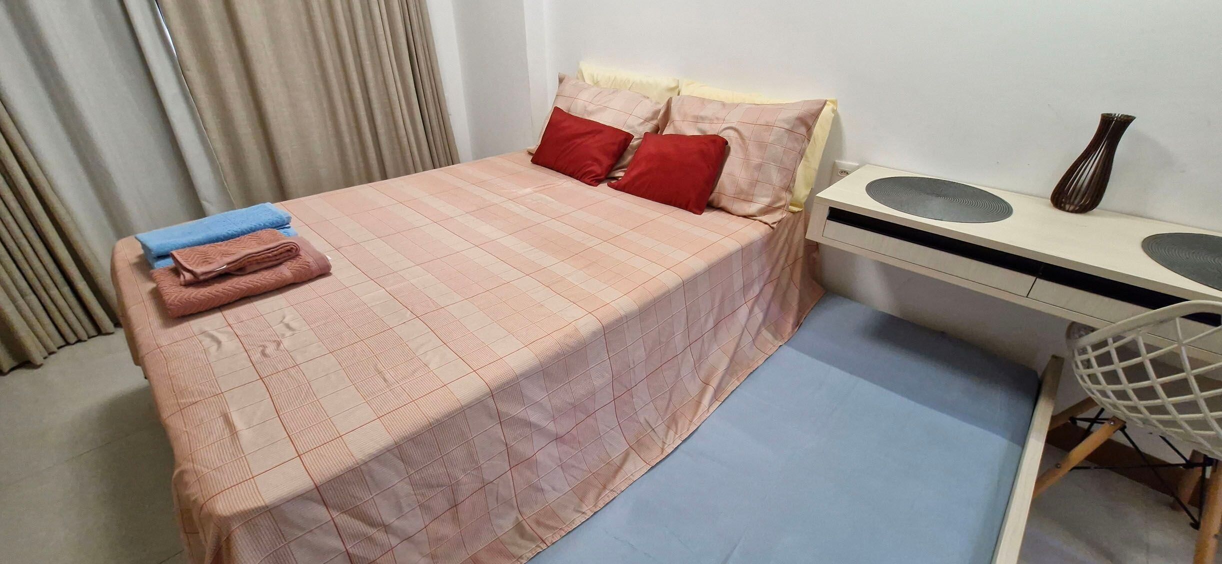 A bedroom with a bed, a desk, and a chair.