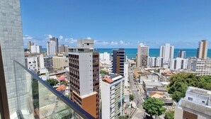 A cityscape with high-rise buildings, a clear blue sky, and a view of the ocean. - COBAR0145 - Edifício ZN Barra (Salvador)