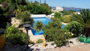 A swimming pool surrounded by lush greenery, with a view of the sea and distant mountains. - Luxurious Ocean View Home in South of France, Close St. Tropez (Fréjus)