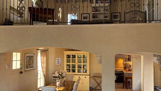 A spacious loft with a high ceiling, exposed wooden beams, a dining area with a wooden table and chairs, and a kitchen visible through an archway. - Luxurious Ocean View Home in South of France, Close St. Tropez (Fréjus)