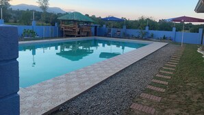 A swimming pool with a tiled deck, a wooden gazebo, and a blue wall. - Spacious 9-bedroom apartment in lovely Bugallon with AC (Bugallon)