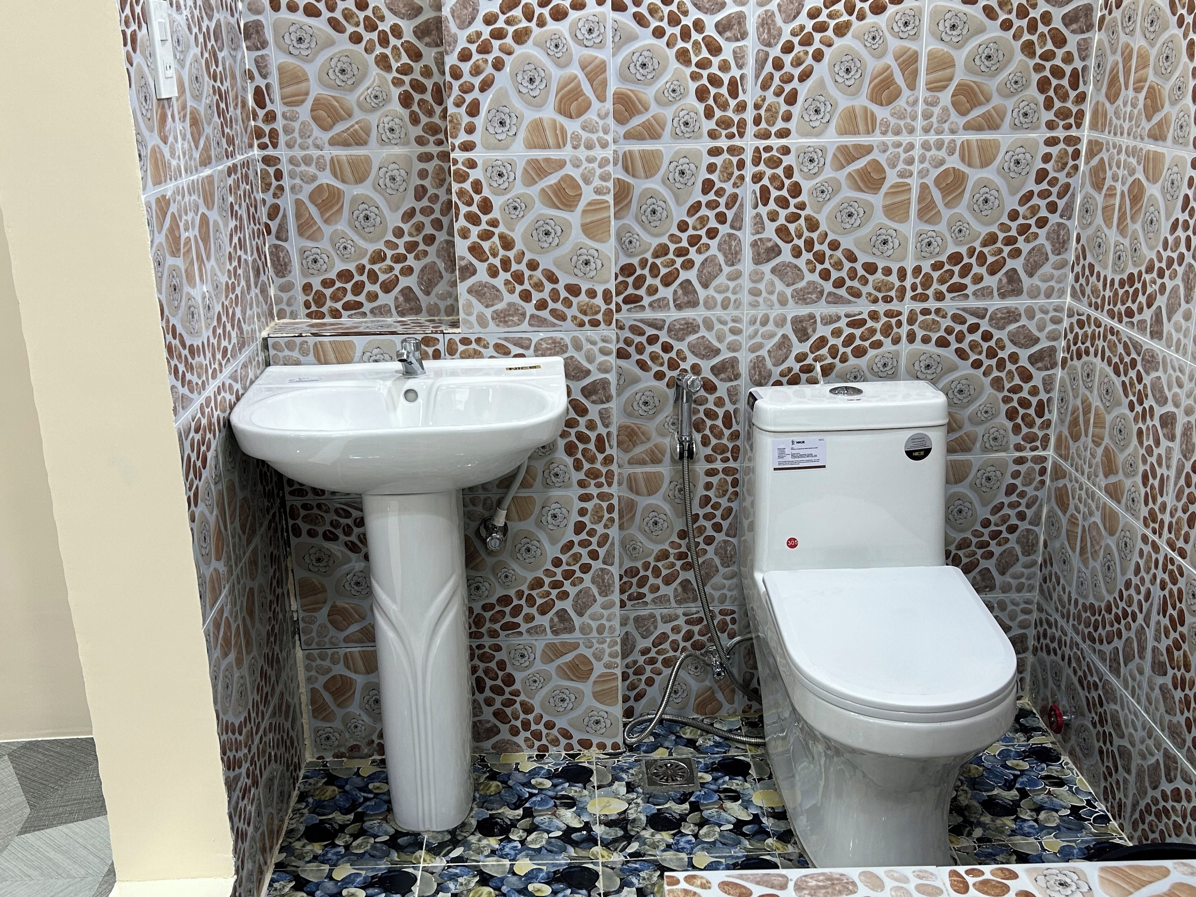 Un bagno con lavandino bianco, servizi igienici e pareti con decorazioni a mosaico.
