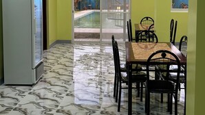 A dining area with a marble floor, a table with chairs, and an air conditioning unit on the wall. - Spacious 9-bedroom apartment in lovely Bugallon with AC (Bugallon)