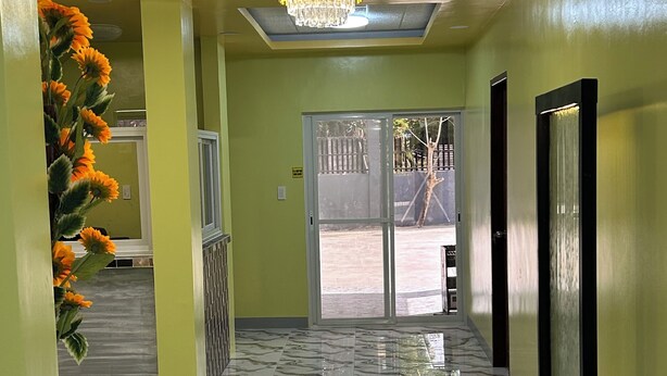 A hallway with a marble floor, a chandelier, and a large window with a view of an outdoor area. - Spacious 9-bedroom apartment in lovely Bugallon with AC (Bugallon)