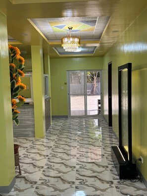 A hallway with a marble floor, a chandelier, and a large window with a view of an outdoor area. - Spacious 9-bedroom apartment in lovely Bugallon with AC (Bugallon)