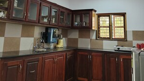 Eine Küche mit Holzschränken, einem Spülbecken, einem Fenster und einem Kühlschrank.