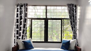 Ein Zimmer mit einem Bett, zwei Kissen und einem Fenster mit Vorhängen.