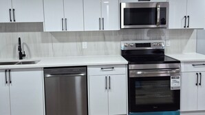 Een moderne keuken met witte kastjes, roestvrijstalen apparatuur en een visgraat houten vloer.