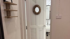 A hallway with a wooden floor, a door with louvered panels, a framed picture on a shelf, and a mirror on the wall. - 3BR Family Villa - 1 km to Chalong Pier With Wifi (Chalong)