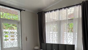 A neatly made bed with white bedding, a dark headboard, and a window with decorative iron bars and sheer curtains. - 3BR Family Villa - 1 km to Chalong Pier With Wifi (Chalong)
