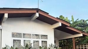 A house with a covered porch, a satellite dish, and a row of large plants in front. - 3BR Family Villa - 1 km to Chalong Pier With Wifi (Chalong)
