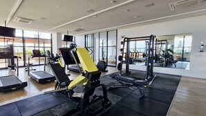 Un gimnasio moderno con cintas de correr, máquinas de pesas y un espejo grande.