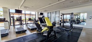 Un gimnasio moderno con cintas de correr, máquinas de pesas y un espejo grande.