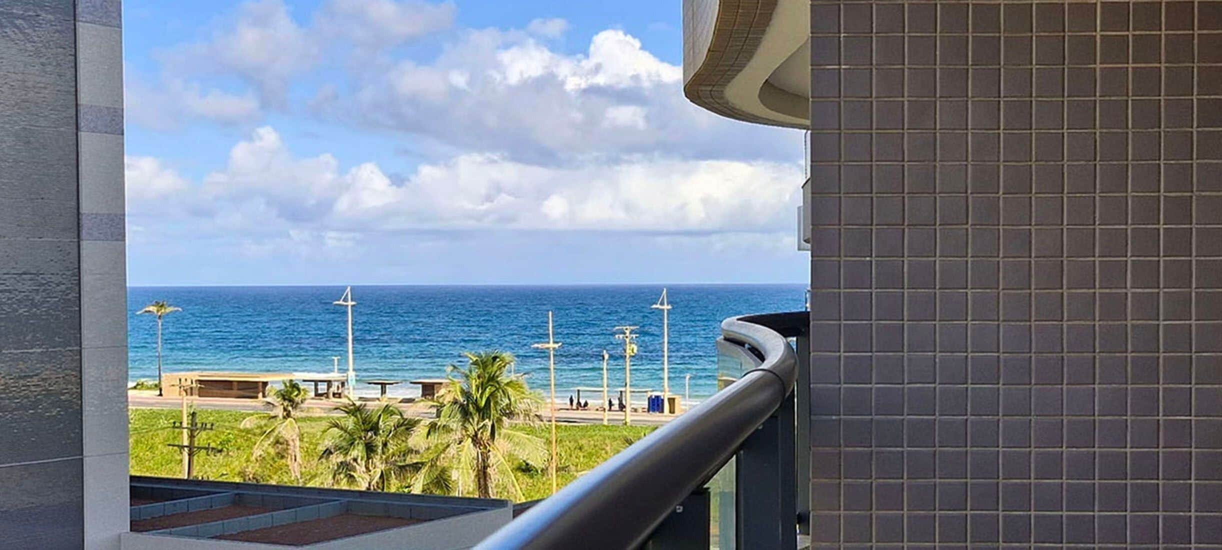 Un balcón con vista al océano y una pared con azulejos.