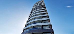 Un edificio alto y moderno con varios balcones y ventanas amplias.