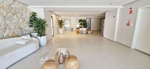 Un vestíbulo moderno con una pared de piedra, un sofá blanco, una mesa de centro de cristal y plantas en macetas.