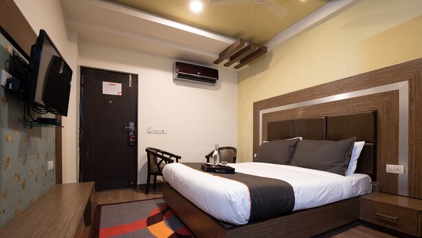 A modern hotel room with a wooden bed, a desk, and a television. - Hotel O Kinfra Industrial Park (Kozhikode)