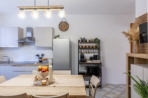 Une cuisine compacte avec des meubles blancs, un four encastré et un coin repas avec une table dressée pour deux personnes.