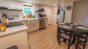 A modern kitchen with a dining area, featuring a microwave, sink, and cabinets. - Stay Roanoke | Roanoke Roost | 2BR + Fire Pit (Roanoke)