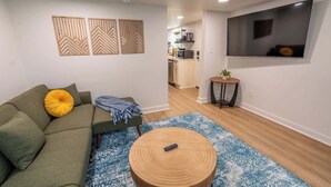 A modern living room with a sofa, a round wooden coffee table, and a patterned rug. - Stay Roanoke | Roanoke Roost | 2BR + Fire Pit (Roanoke)