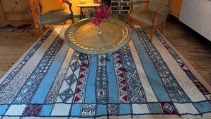 A cozy room with a fireplace, two wicker chairs, a round table with a vase, and a patterned rug. - Private 2-bedroom apartment at Château de La Coste (Saint-Julien)
