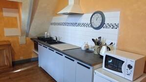 A kitchen with a wooden floor, white cabinets, a black countertop, a white stove, and a clock on the wall. - Private 2-bedroom apartment at Château de La Coste (Saint-Julien)
