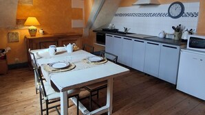 A kitchen with a dining table, white cabinets, and a stove. - Private 2-bedroom apartment at Château de La Coste (Saint-Julien)