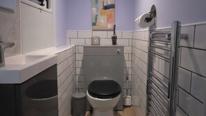 Een kleine badkamer met toilet, bidet en een handdoekhouder.