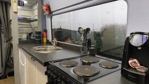 A compact kitchen with a sink, stove, and a coffee machine. - Railway train carriage beautifully converted for an unusual stay in Countryside (ELY)