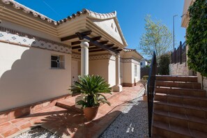A building with a tiled roof, a covered patio area, and a staircase leading to an upper level. - 3BR Apartment With Private Garden (Alhaurin de la Torre)