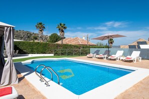 A swimming pool with lounge chairs, a tent, and a view of a mountain and palm trees. - 3BR Apartment With Private Garden (Alhaurin de la Torre)