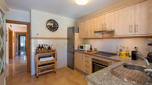 Una cucina con mobili in legno, un frigorifero in acciaio inossidabile, un forno a microonde e un lavandino.