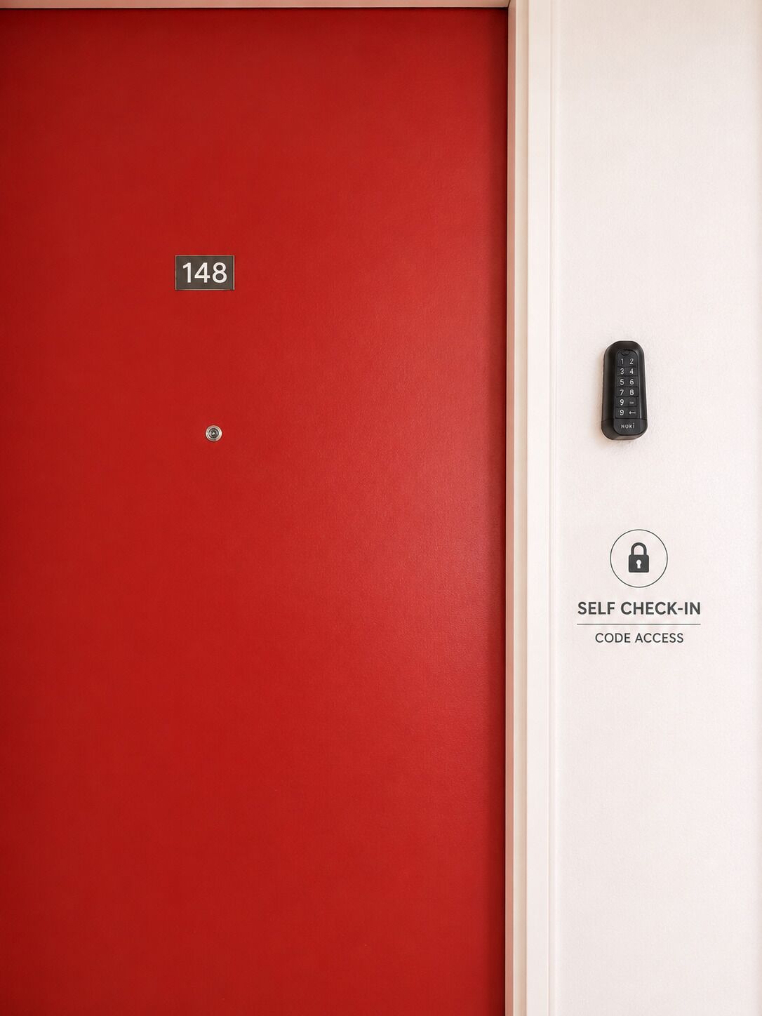 Une porte rouge avec une plaque portant le numéro « 148 » et un panneau d’accès avec un code pour l’enregistrement autonome, situé sur le mur adjacent.