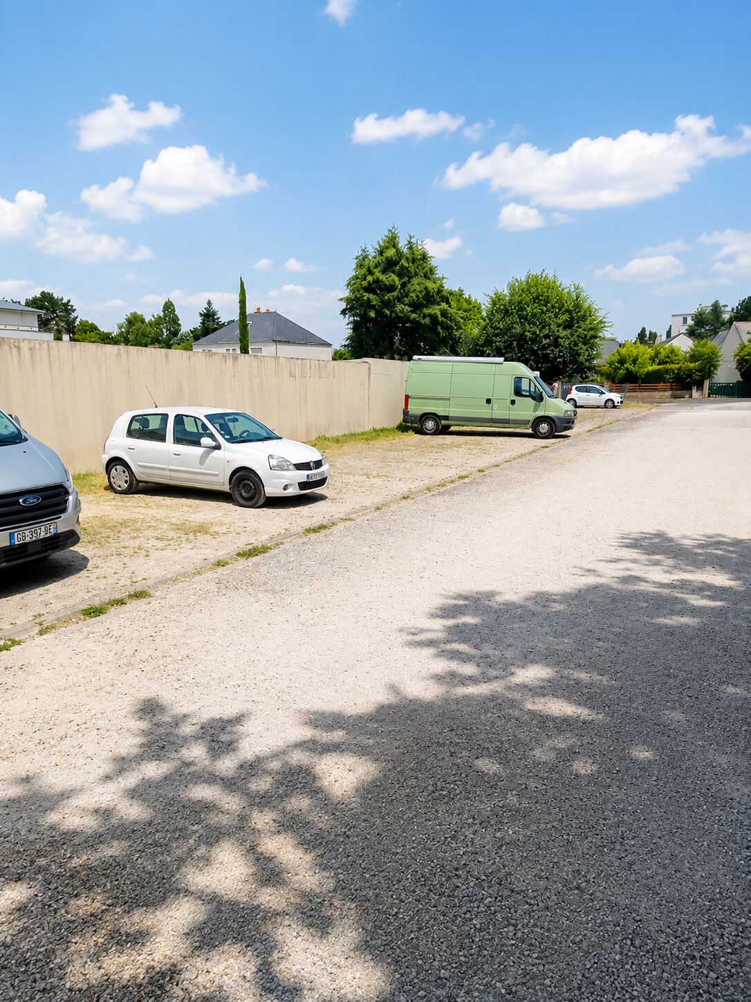 Ein Parkplatz mit Kiesbefestigung und einer Betonmauer.