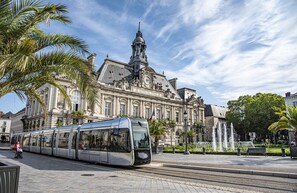 A modern tram in front of a historic building with a prominent tower and classical architecture. - Spacious 3-bedroom apartment in Tours Nord near the tramway (Tours)