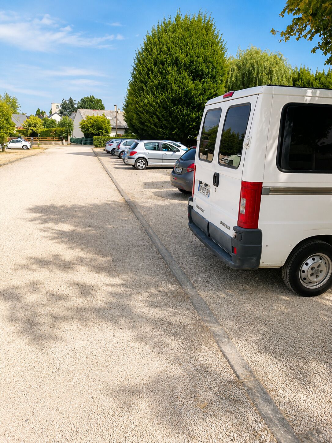 A parking lot with several cars and a white van.