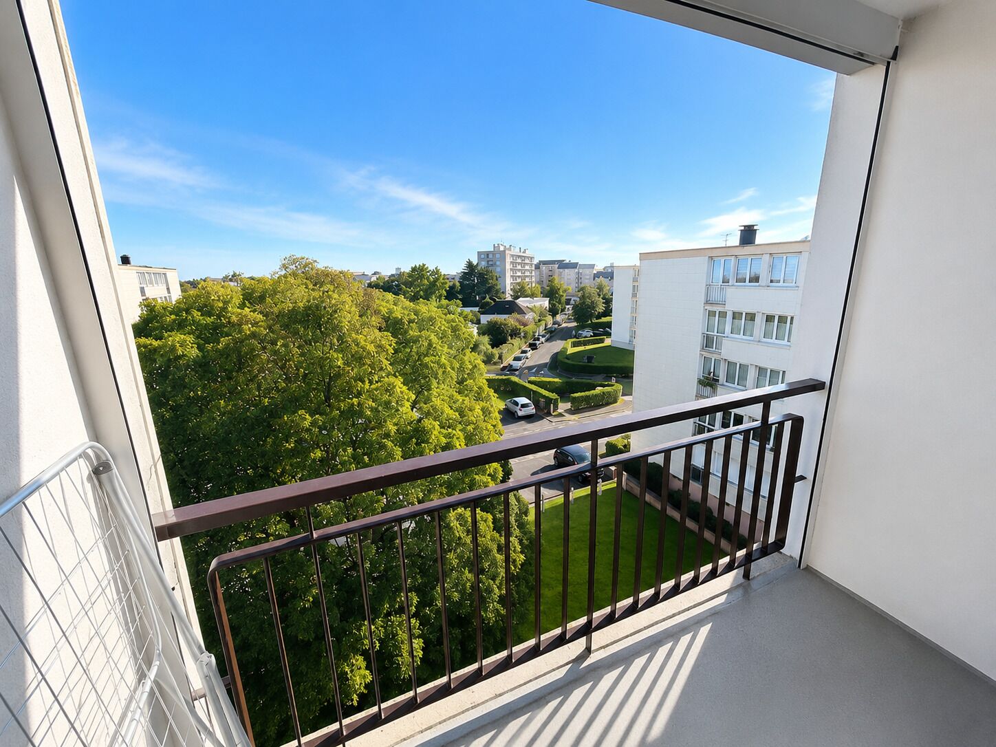 Ein Balkon mit Blick auf ein Wohngebiet, inklusive Gebäude und Grünflächen.