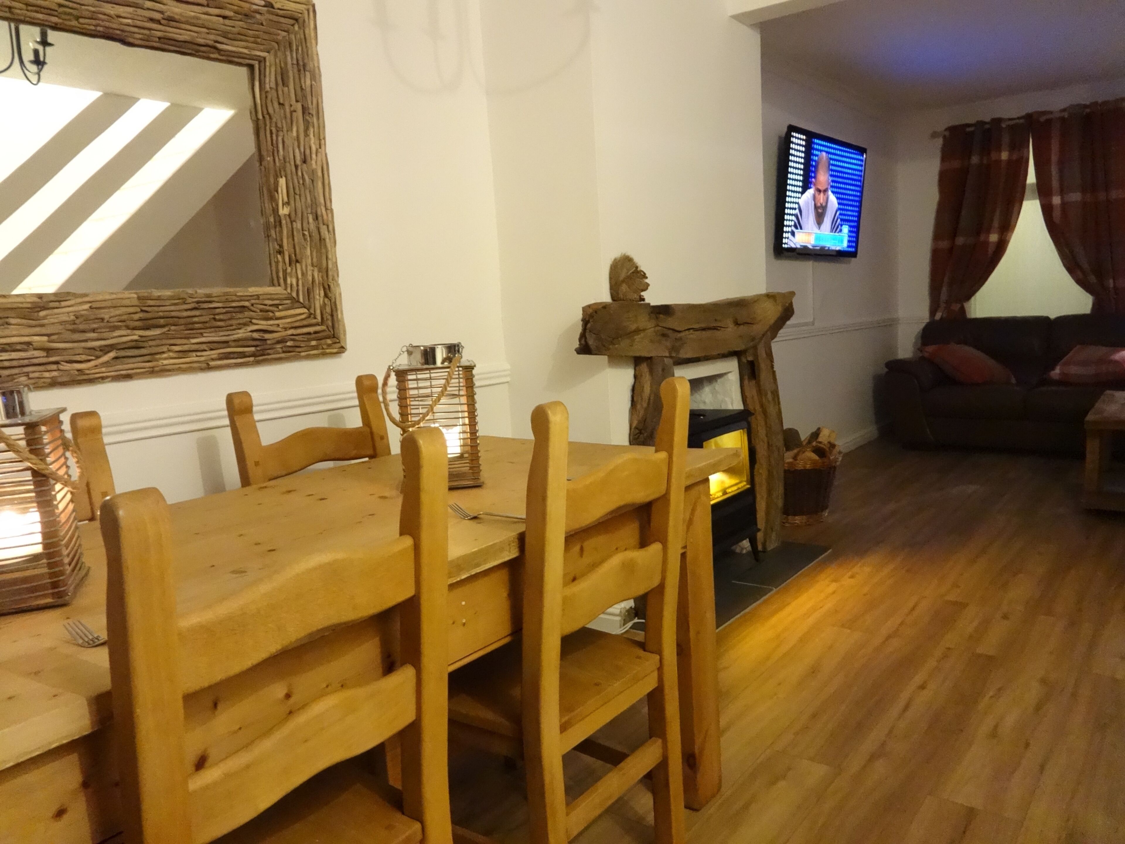 Uma sala de estar com uma mesa e cadeiras de madeira, lareira, televisão e sofá.