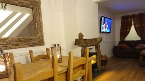 Un comedor con una mesa y sillas de madera, una chimenea, un televisor y un sofá en una sala de estar.