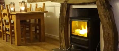 A room with a fireplace, wooden chairs, and a table.