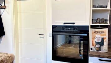 Eine Küche mit weißen Schränken, einem schwarzen Backofen und einer grünen Aufbewahrungsbox.