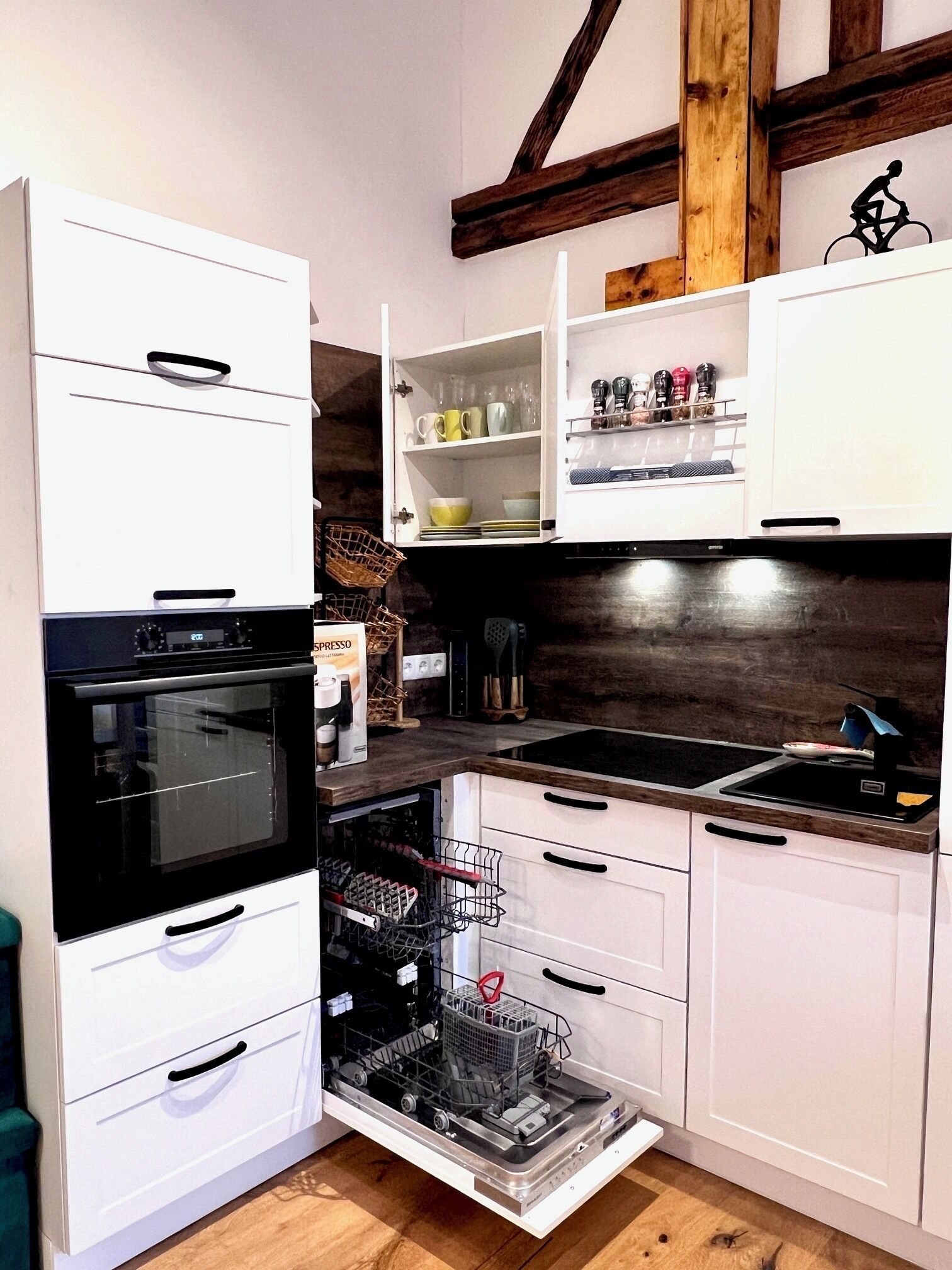 A kitchen with white cabinets, a black oven, a dishwasher, and a wooden ceiling.