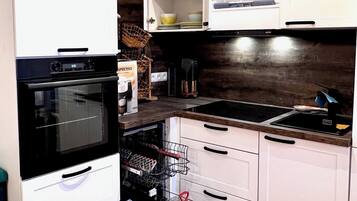 A kitchen with white cabinets, a black oven, a dishwasher, and a wooden ceiling.