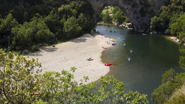 Una playa con un arco natural de roca, rodeada de abundante vegetación.