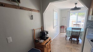 A compact kitchen with a bench, a coffee maker, and a dining area with a table and chairs.