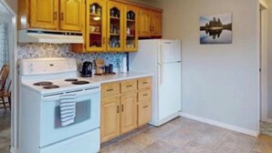A kitchen with wooden cabinets, a white stove, and a refrigerator.